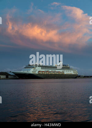 Ein Kreuzfahrtschiff ist während des Sonnenuntergangs am Honolulu Hafen verankert. Stockfoto