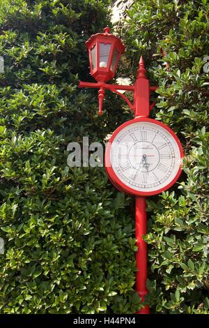 Rote Vintage Metall Park Uhr auf grüner Baum Blatt Hintergrund Stockfoto