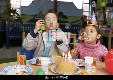 Kinder Geburtstagsparty, junge, Mädchen, Papierhüte, Seifenblasen, Kuchen, Kerzen, brennen, Menschen, Kinder, Geschwister, Geburtstagstorten, Party, Geburtstagsparty, feiern, Vergnügungen, glücklich, spielen, Party-Mützen, Kopfbedeckungen, Spaß, Freude, fröhlich, Stockfoto