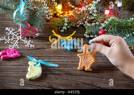 Das Kind hält eine Girlande von Weihnachtsschmuck aus Salzteig. Kinder Kunst-Projekt, ein Handwerk für Kinder. Stockfoto