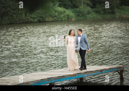 elegante stilvolle Bräutigam mit seiner glücklich wunderschöne Brünette Braut auf dem Hintergrund eines Sees Stockfoto