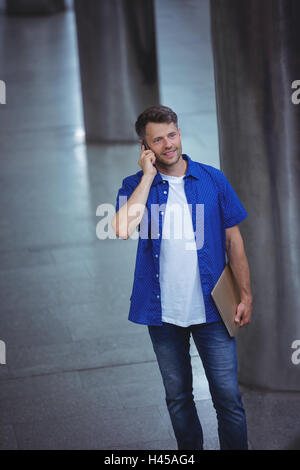 Gut aussehender Mann hält Laptop und telefonieren mit Handy Stockfoto