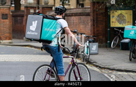 Deliveroo Radfahrer aus dem beliebter heiße Nahrung und Fast Food Lieferung Unternehmen Fahrrad durch die Straßen der Stadt. Stockfoto