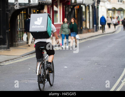 Deliveroo Radfahrer aus dem beliebter heiße Nahrung und Fast Food Lieferung Unternehmen Fahrrad durch die Straßen der Stadt. Stockfoto