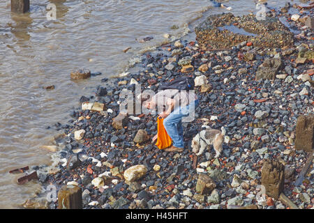 Ein Mann und sein Hund-Mudlarking auf der Themse Vorland in der Nähe von Southwark bridge Stockfoto