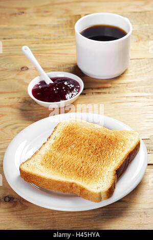 Gebratenes Toastbrot mit Himbeermarmelade und Tasse Kaffee auf alten Holztisch Stockfoto