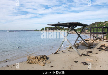 Ruhigen Indischen Ozean und Strand mit Unterkunft und bewachsenen Dünen an der Küste bei bewölktem Himmel auf Penguin Island in Western Australia. Stockfoto