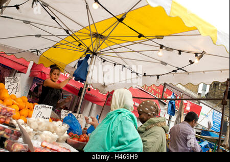 Hackney. Ridley Straße Markt. Zwei Frauen tragen Kopftücher Shop an einen Obst und Gemüse Stall. Stockfoto