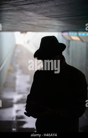 Silhouette des Mannes in Trilby und Mantel, in eine Unterführung London, UK Stockfoto