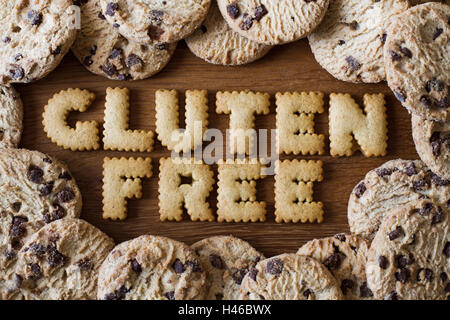 Die Lebensmittel-Beratung "Glutenfrei" buchstabiert mit Alphabet Cookies geformt und umgeben von Gluten frei, chocolate Chip Cookies auf Holz Stockfoto