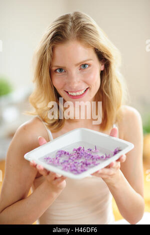 Blonde Frau hält Peel mit Blütenblättern, Stockfoto