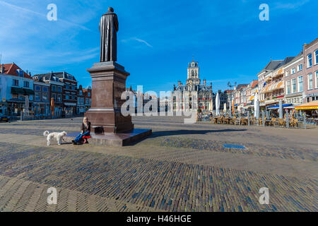 DELFT, Niederlande - 4. April 2008: Ein junges Mädchen mit einem Hund sitzt auf ein Denkmal für den niederländischen Jurist Hugo Grotius Stockfoto