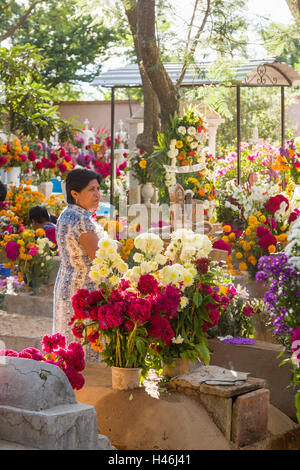 Eine Frau Ansichten Grabstätte verziert mit aufwendigen floralen Pedal Wandteppiche zu Ehren des Verstorbenen auf dem Friedhof San Antonino Castillo im Laufe des Tages von den Dead Festival bekannt als D'a de Muertos am 3. November 2013 in San Antonino Castillo Velasco, Oaxaca, Mexiko. Stockfoto