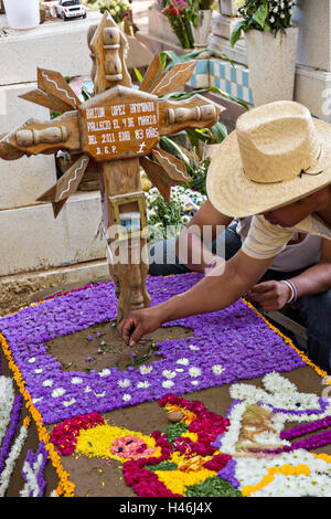 Menschen dekoriert ein Graves mit aufwendigen floralen Pedal Wandteppiche zu Ehren des Verstorbenen auf dem Friedhof San Antonino Castillo im Laufe des Tages von den Dead Festival bekannt als D'a de Muertos am 3. November 2013 in San Antonino Castillo Velasco, Oaxaca, Mexiko. Stockfoto