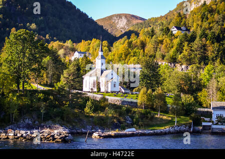 weiße Stabkirche im kleinen Dorf am Fjord Küstenblick vom Boot Stockfoto