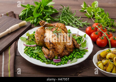 Gegrilltes Bio Bio Huhn, Bratkartoffeln, mit Frühling Gemüse und Kräutern, mit Bier Stockfoto