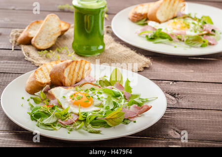 Leichter Sommersalat mit Spiegelei und Nüssen, Kräutern und Avocado Smoothie mit Spinat, toast panini Stockfoto