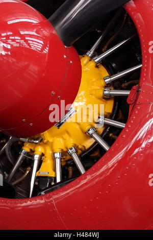 Nahaufnahme einer roten Propeller Nase mit einem gelben Motor und Metallstangen Stockfoto