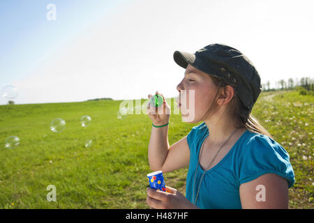 Mädchen Puffs Seifenblasen, Sommer, draußen, Porträt, seitlich, Stockfoto