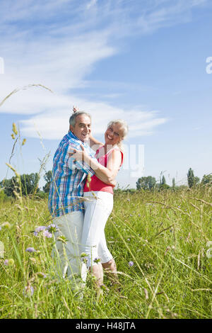 Senioren Paartänze in einer guten Stimmung über eine Wiese, Stockfoto