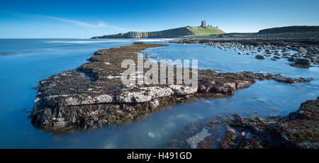 Dunstanburgh Castle von Felsvorsprüngen Embleton Bay, Northumberland, England. Frühling (März) 2014. Stockfoto