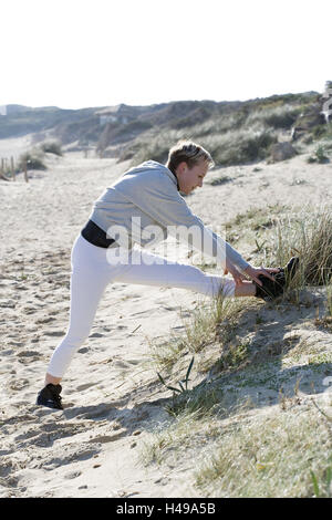 Frau, Sportkleidung, Dünen, Dehnübung, Model Release, Menschen, sport, sportlich, Freizeit, Erholung, Urlaub, Bewegung, Aktivität, Spaß, Lächeln, laufen, Joggen, Fitness, Stretching, Praxis, Blähungen, Strand, Ganzkörper, Seitenansicht, Stockfoto