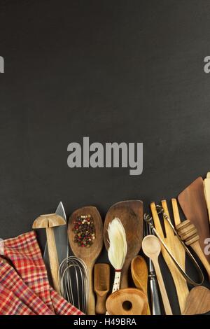Küchenutensilien auf Holztisch. Werkzeuge kochen. Kochen muss. Satz von der hölzernen Küchenutensilien auf schwarzem Hintergrund aus Holz. Stockfoto