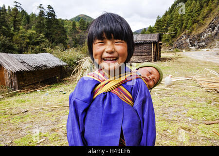 Königreich Bhutan, Kind tragen Baby auf dem Rücken, Stockfoto