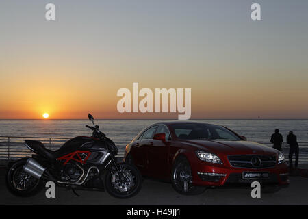 Motorrad, Ducati Diavel und Mercedes CLS 63 AMG rot, Musclebike, Sonnenuntergang, Strand, Menschen im Hintergrund, Stockfoto