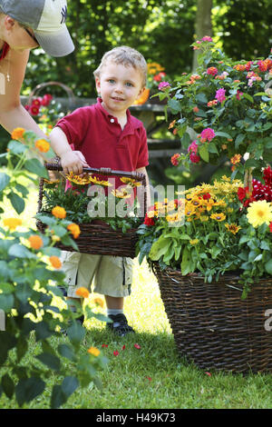 Kleines Kind, junge mit Korb mit Blumen im Garten, Sonnenhut, spanische Flagge, Gazanie, spanische Flagge, Dahlie, Rudbeckia, spanische Flagge, Gazanien, Dahlie, Stockfoto