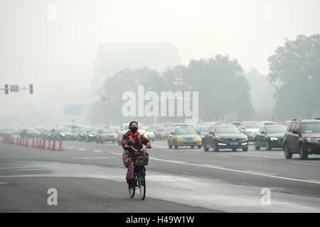 Peking, China. 14. Oktober 2016. Eine Frau mit Maske reitet auf einem Smog gehüllten Straße in Peking, Hauptstadt von China, 14. Oktober 2016. Bildnachweis: Ju Huanzong/Xinhua/Alamy Live-Nachrichten Stockfoto