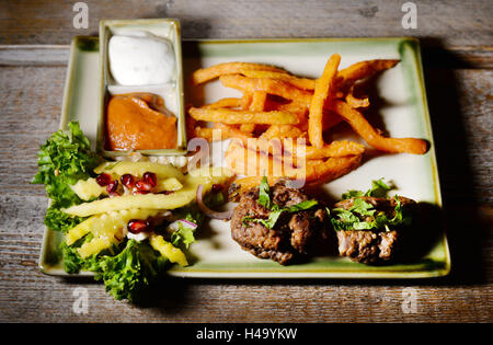 Berlin-Frikadellen mit vietnamesischen Gewürzen und Pommes frites gemacht von Süßkartoffeln mit Birne-Curry Ketchup und Chili-Limetten-Mayonnaise zusammen mit Mango Sauerkraut Salat und Granatapfel Perlen, Äpfel, Chesnuts und Koriander liegt auf einer Platte an der vietnamesischen Restaurant Anjoy in Rykestraße im Stadtteil Prenzlauer Berg in Berlin, Deutschland, 13. Oktober 2016. Es bietet Klassiker aus der Berliner Küche in ihre vietnamesische Version als Kombination von zwei Esskulturen in einer Aktionswoche unter dem Motto "Berlin Frikadellen auf eine Reise durch Vietnam".  Das Menü wurde von Internet Köche Henriette Wulff Stockfoto