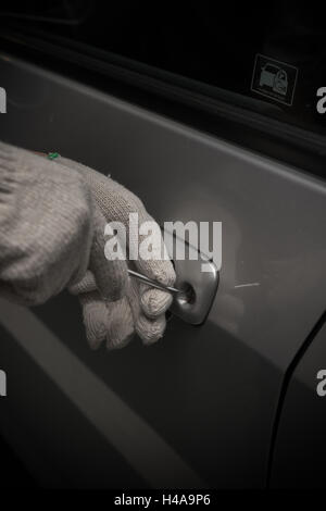 Autodieb mit Handschuh versucht eine Fahrzeugtür mit Schraubenzieher zu öffnen Stockfoto