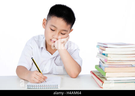 Gelangweilt asiatische chinesische wenig junge tragen Schüler einheitliche Writting Heimarbeit in isolierten weißen Hintergrund. Stockfoto