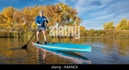 Senior männlichen Paddler genießt Training auf seinem Renn-Stand up Paddleboard auf einem See in Herbstfarben in northern Colorado Stockfoto