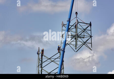 Männer arbeiten in den Hochspannungs-Stromversorgung Pylon, Kran heben Teil des Mastes, Thüringer Wald Stockfoto