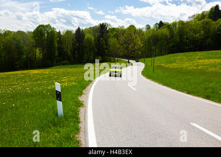 Deutschland, Bayern, grünes Auto fahren auf der Landstraße im Frühjahr Stockfoto