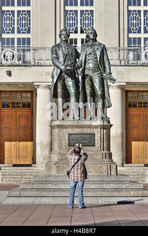 Deutschland, Thüringen, Weimar, Tourist nimmt ein Foto von dem Goethe und Schiller-Denkmal vor dem Nationaltheater, Stockfoto