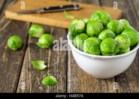 frischer Rosenkohl in weiße Schüssel auf Holztisch Stockfoto