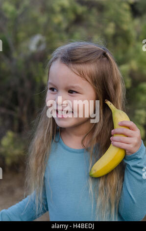 Kleines Mädchen nutzt eine Banane als Handy-Nummer Stockfoto