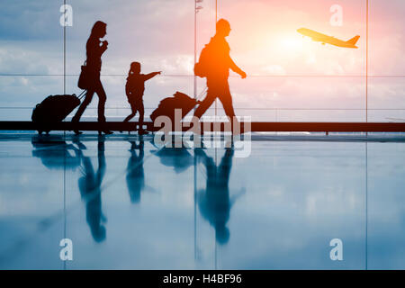 Silhouette der jungen Familie und Flugzeug am Flughafen Stockfoto