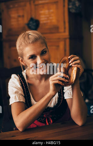 Frau sitzt am Tisch mit Bierkrug und Brezel Stockfoto