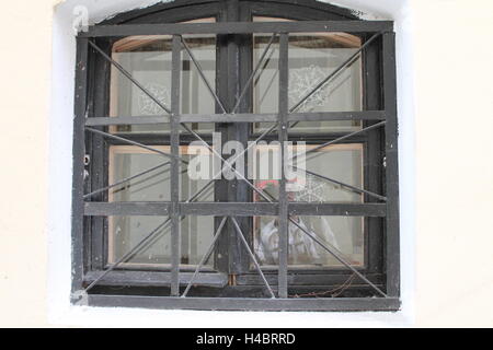 Retro-Stil Form Bogen kleine Fenster, Glas, geteilt in vier Teile, bedeckt schwarze Metallgitter Dekor und Schutz Stockfoto