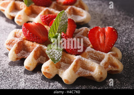 Frisch gebackene Waffeln mit frischen Erdbeeren, bestreut mit Puderzucker Nahaufnahme auf der Schiefertafel. Stockfoto