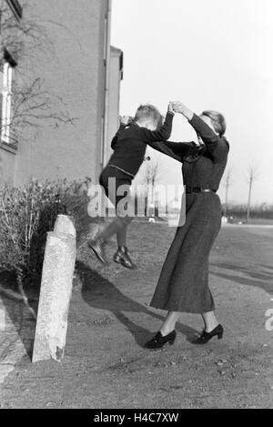 Mitglieder Einer Kinderreichen Familie Spielen Vor Dem Wohnhaus, 1930er Jahre Deutsches Reich. Mitglieder einer Großfamilie spielen vor dem Apartmentgebäude, Deutschland der 1930er Jahre Stockfoto