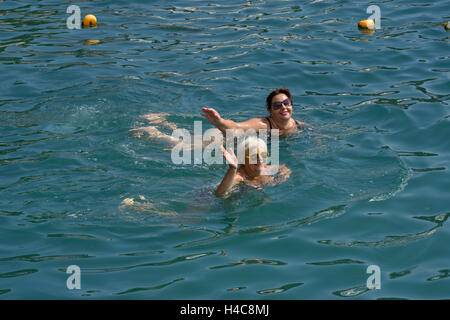 Zwei Frauen, senior blonde und Reife Dicke Brünette, die ihre Hände in Salut beim Schwimmen im klaren Wasser des Meeres erhoben. Stockfoto