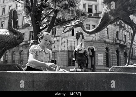 Eine Junge Frau Probiert Das Warme Thermalwasser aus Dem Reiherbrunnen in der Sophienstraße der Innenstadt von Baden-Baden, Deutschland, 1930er Jahre. Eine junge Frau schmeckt das warme Thermalwasser aus der Reiherbrunnen in der Sophienstraße in die Stadt centr Stockfoto