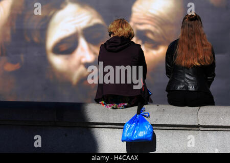 Zwei Frauen sitzen auf einer Mauer vor einem Horten am Trafalgar Square in London, England Stockfoto