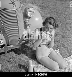 Eine Frau Beim Picknick Vor Einem Ford V6, 1930er Jahre Deutschland. Eine junge Frau, die einen Picknick vor der ein Ford V8, Deutschland der 1930er Jahre. Stockfoto