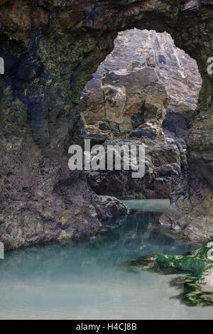 Meer-Bogen am Perranporth bei Ebbe. Meer Arch und Rock pool an der kornischen Küste. Küstenlandschaft in Cornwall bei Ebbe. Stockfoto